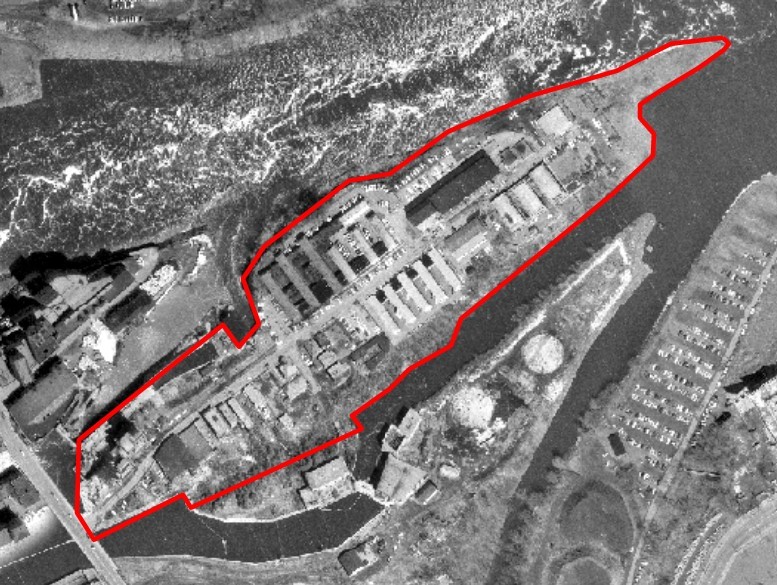 Black and white aerial view of the island, with the edges of the island indicated by a red line.