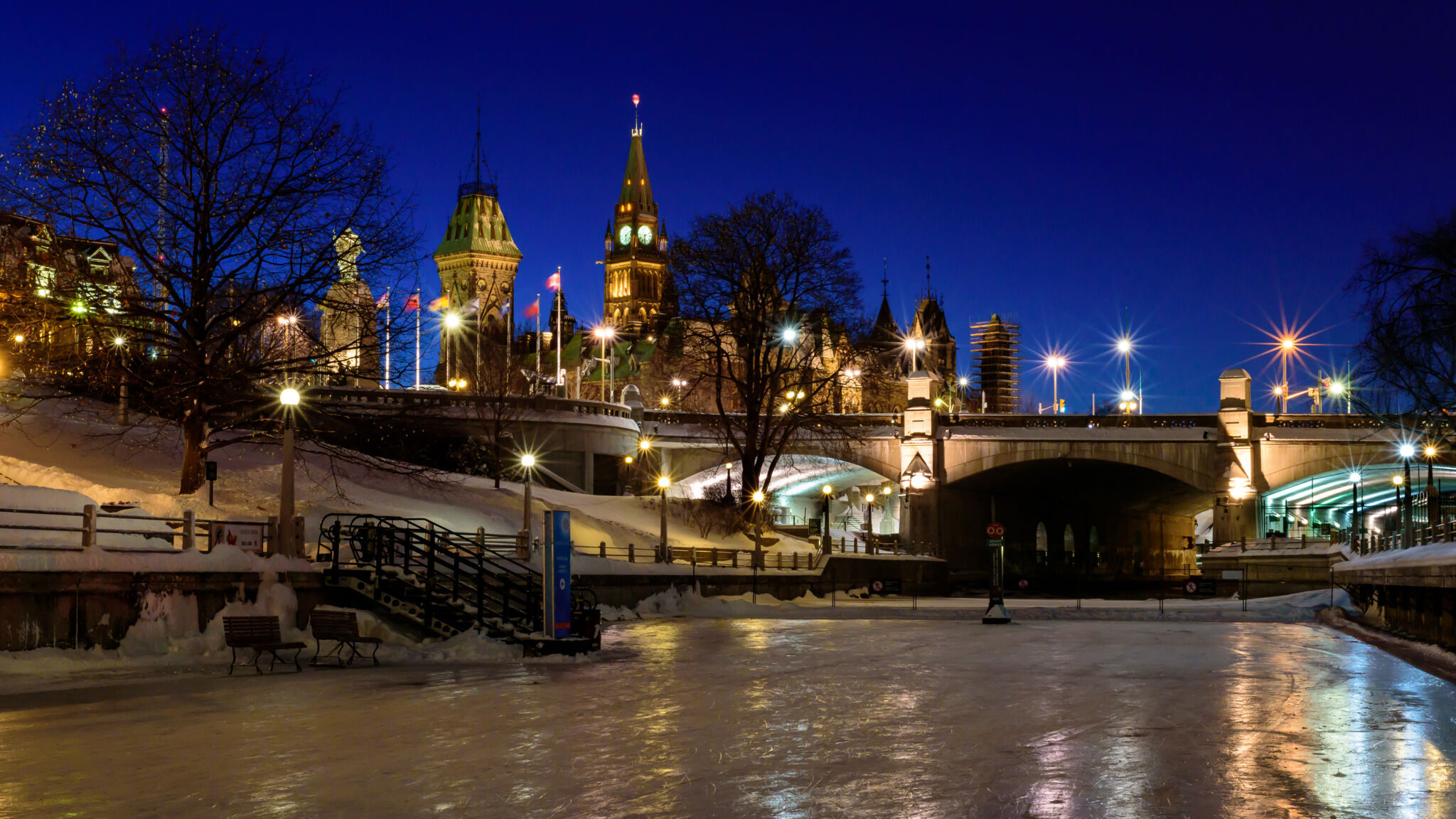 Vue en soirée de la patinoire du Canal Rideau avec le Parlement en arrière-plan.