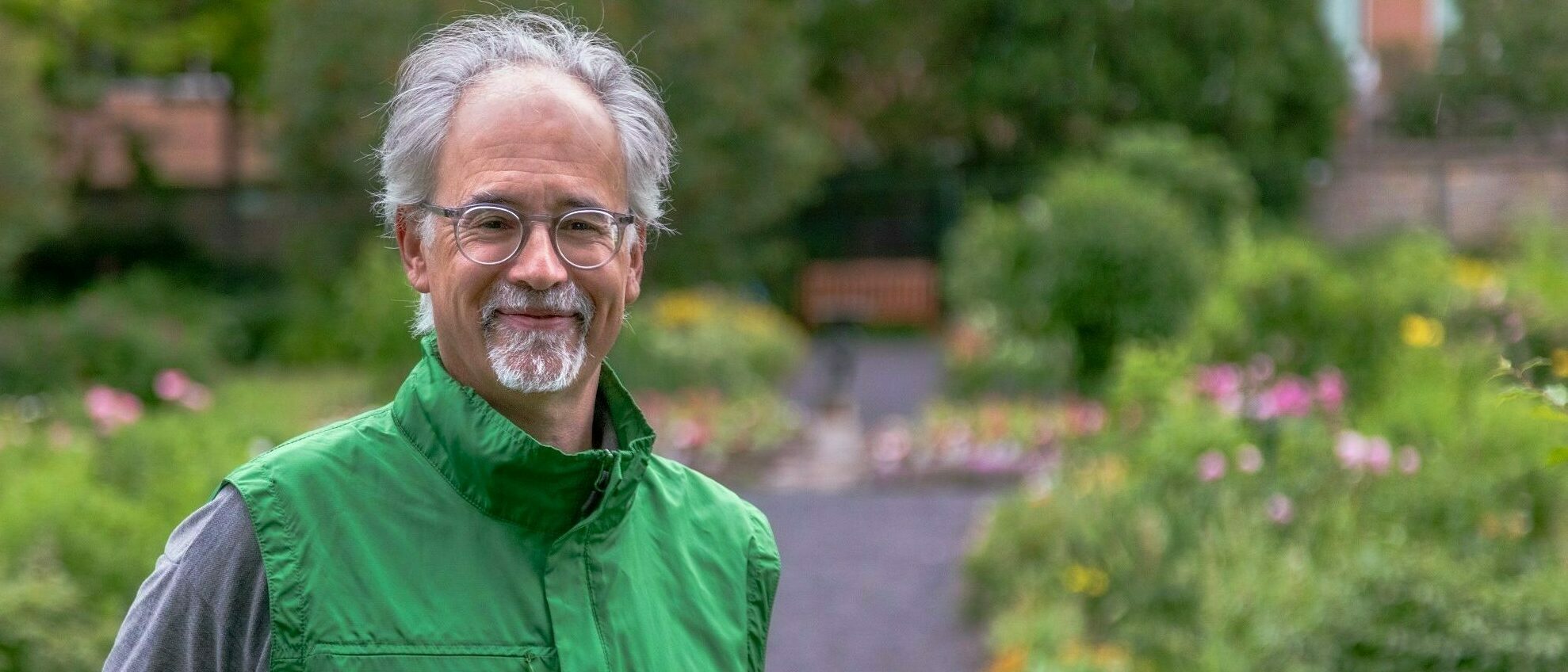 Volunteer wearing an NCC volunteer vest, standing in a garden, facing the camera.