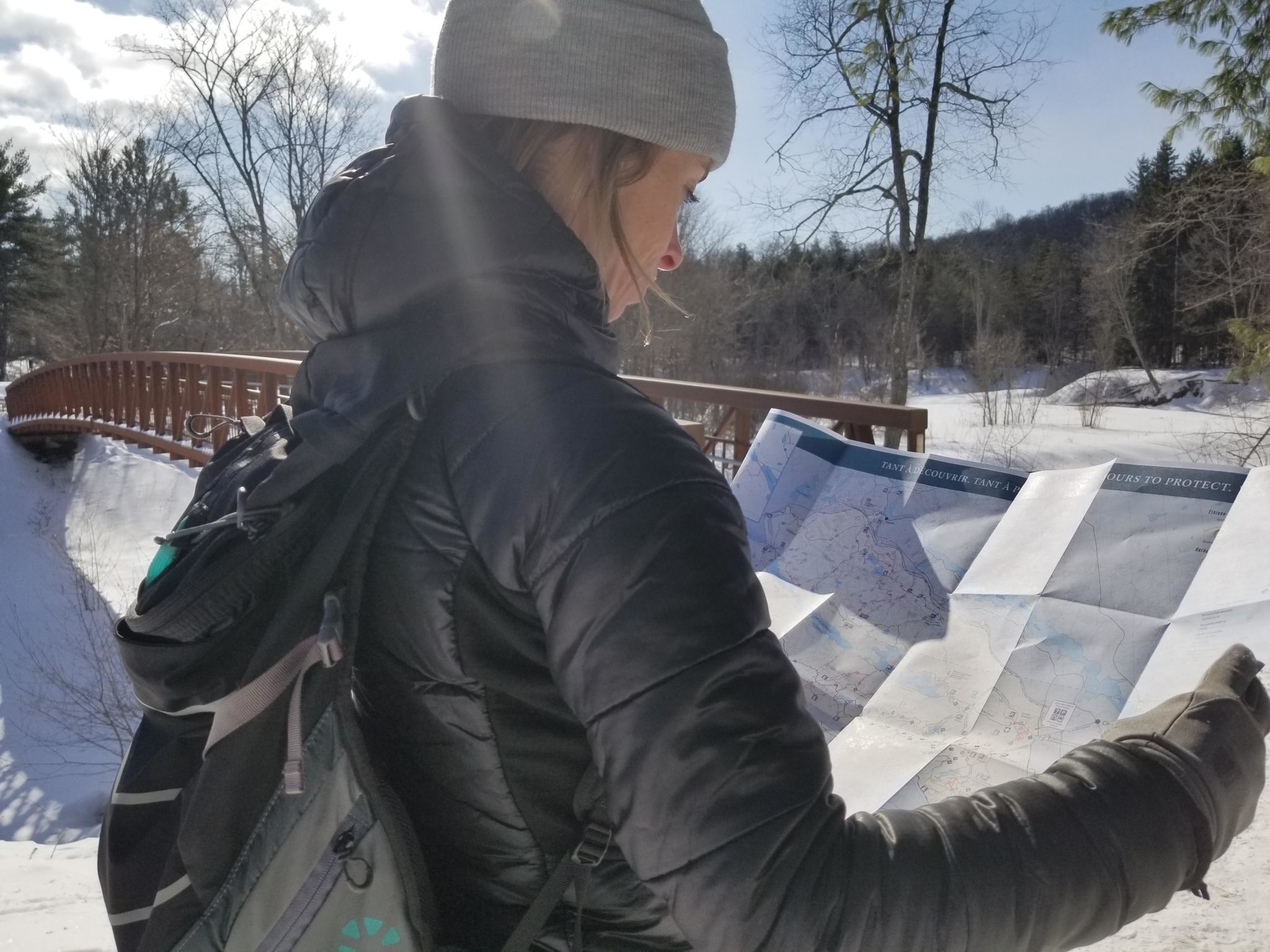 A hiker reading the Gatineau Park winter trail map