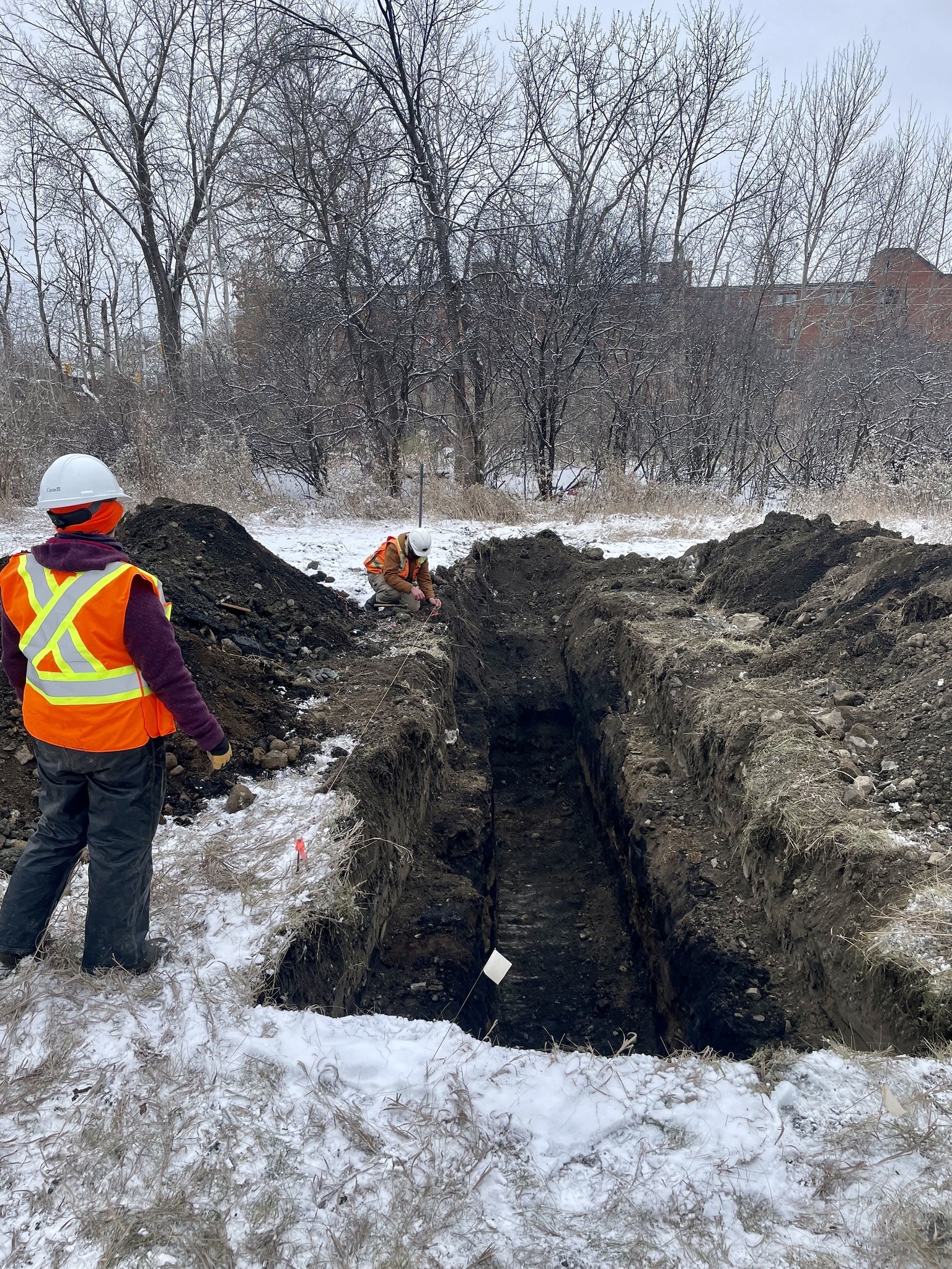 Une personne travaille à côté d’une fosse creusée mécaniquement.