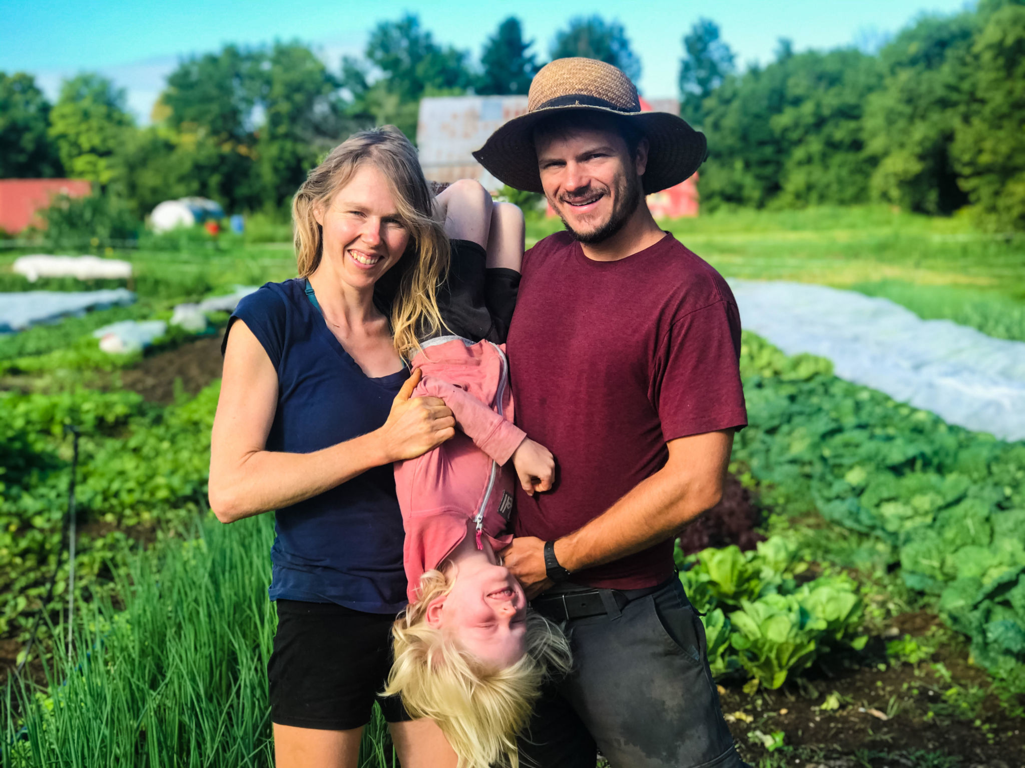 Jonathan et Jolianne, cofondateurs de Farm Fresh, posant devant un champ avec leur enfant.