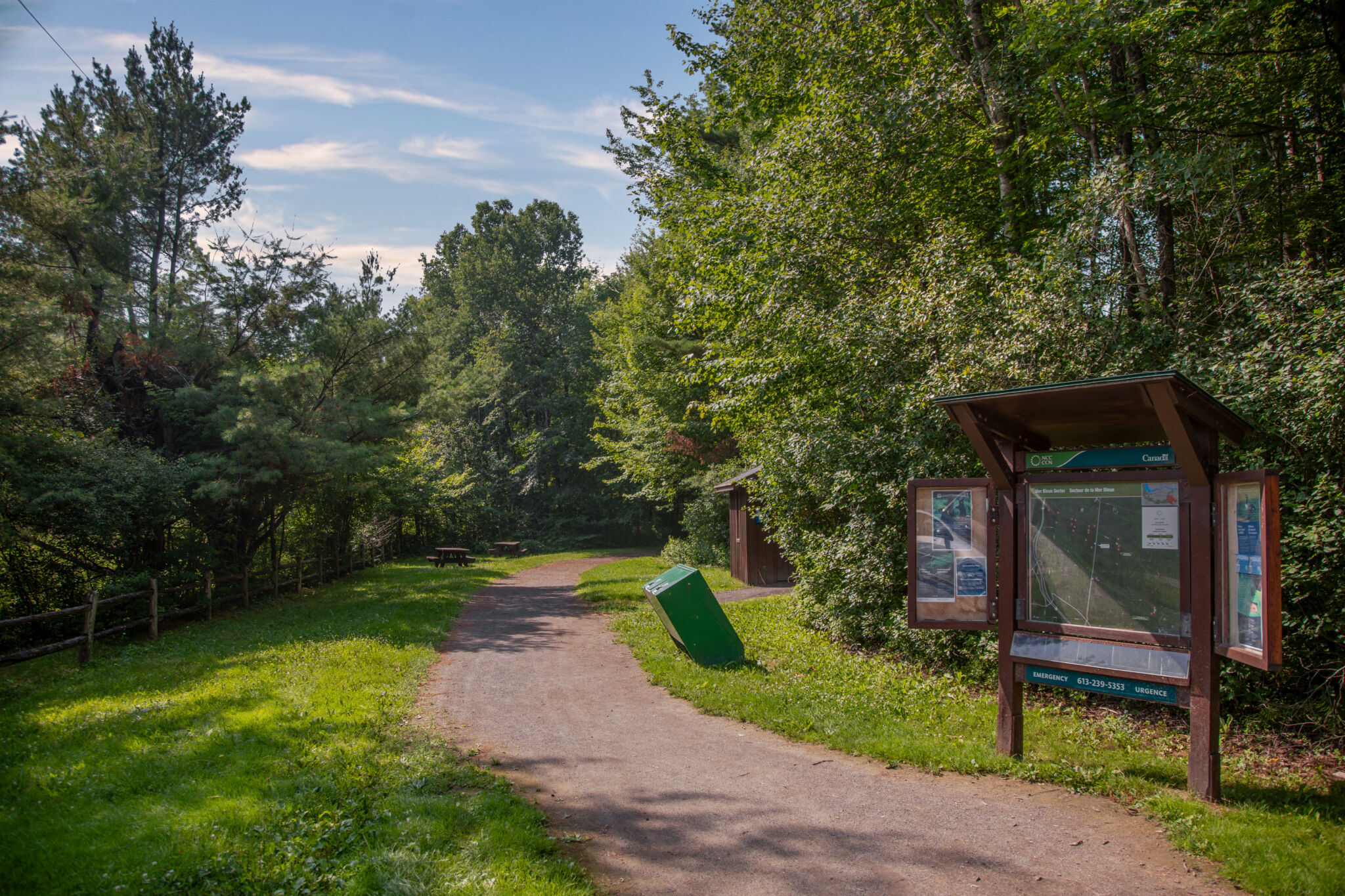 A trail in the Greenbelt with signage and surrounding trees