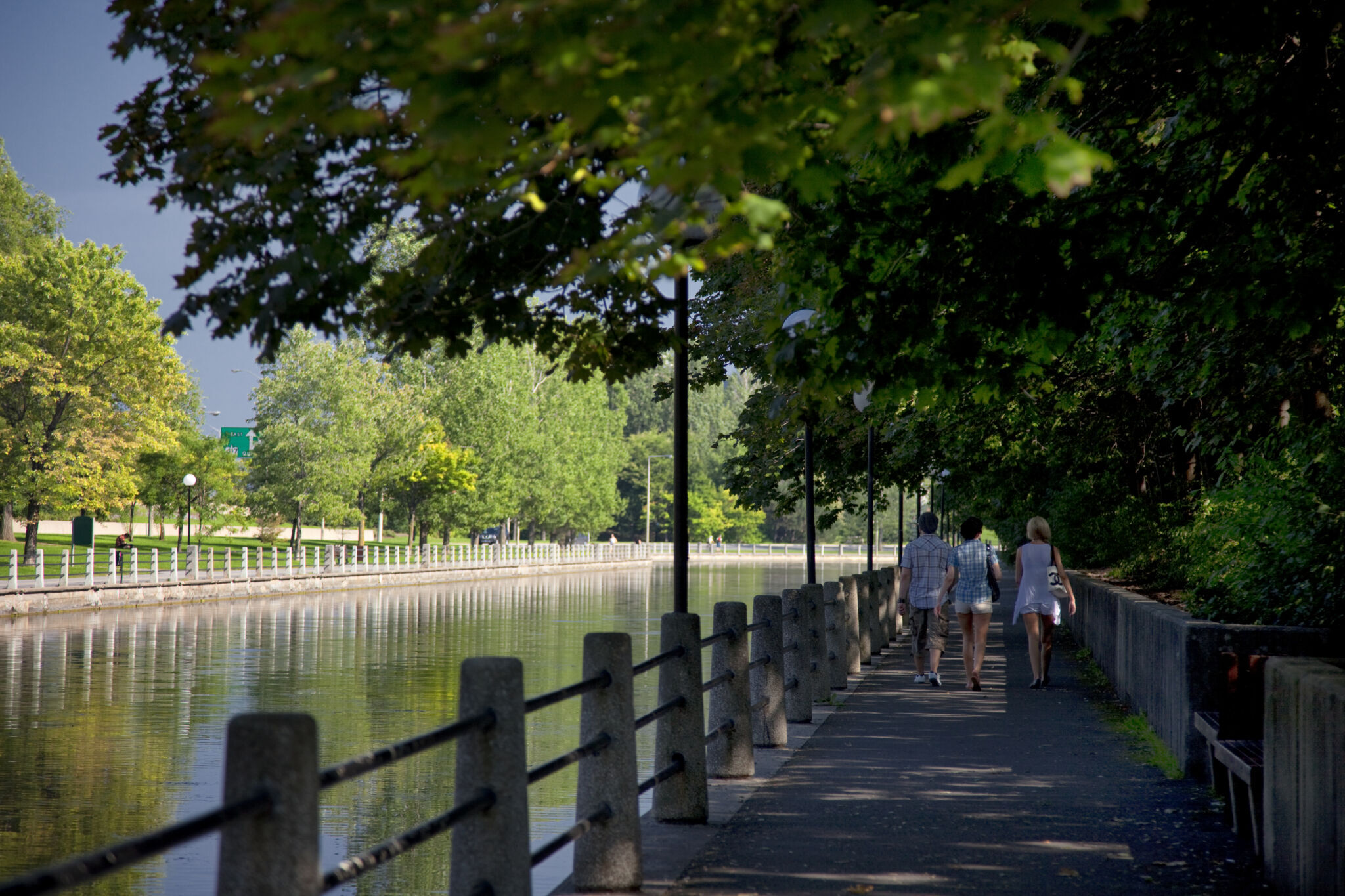 Three people walking along the Rideau Canal pathway.