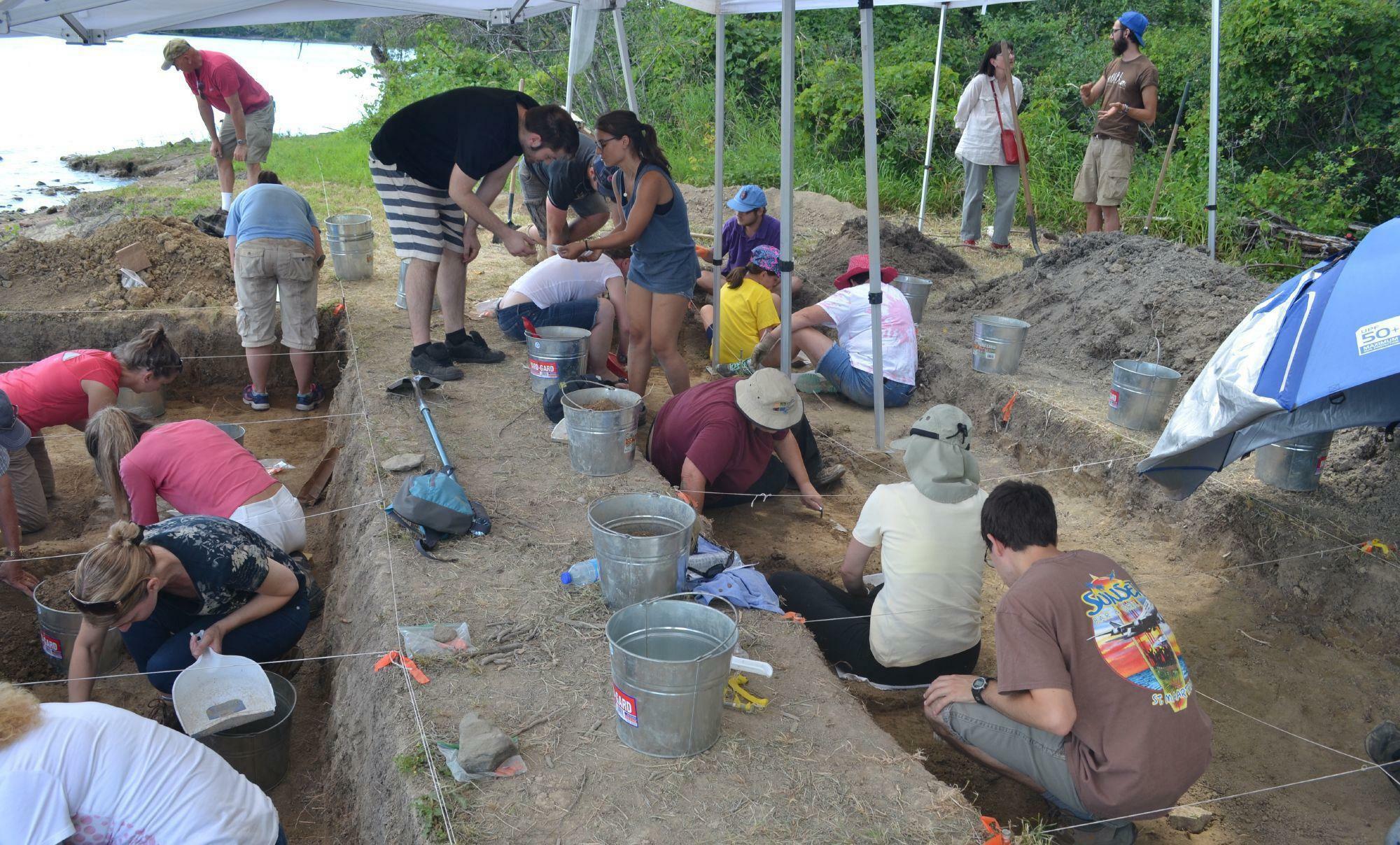 People engaged in archaeological digs by the shore of the Ottawa River.