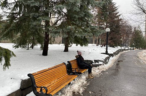 Une personne assise sur un banc de parc en hiver.