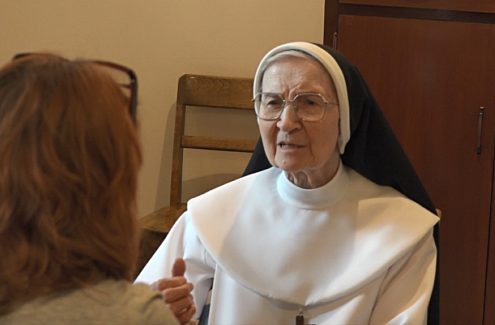 Sœur Marie-Jeanne-du-Lys, portant un costume religieux, donne une entrevue à Marie Roy, qu’on voit de dos sur la photo.