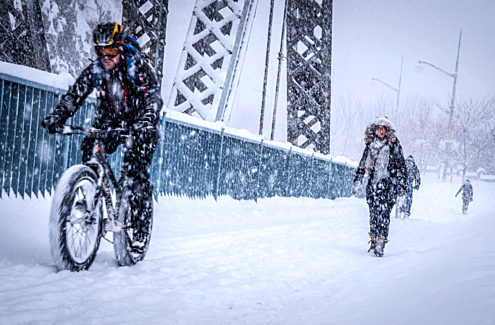 Cyclists and pedestrians on the Alexandra Bridge walkway on a snowy day. Credit: NCC