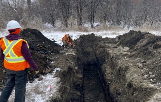Worker beside a mechanically dug pit.