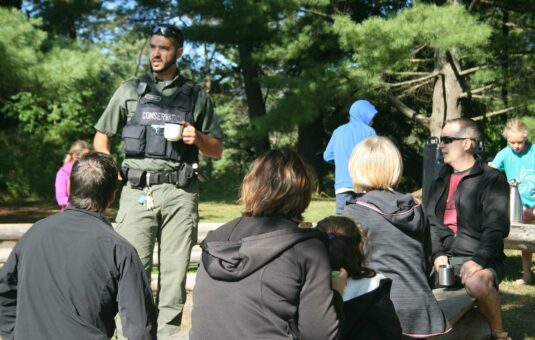 Conservation officer, coffee in hand, with members of the public.