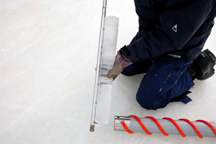 An employee measuring an ice carrot, drilled from the frozen canal.