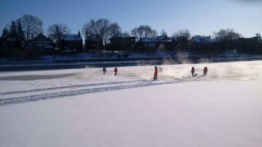 Maintenance staff pumping water at the surface of the snow-covered Rideau Canal Skateway.