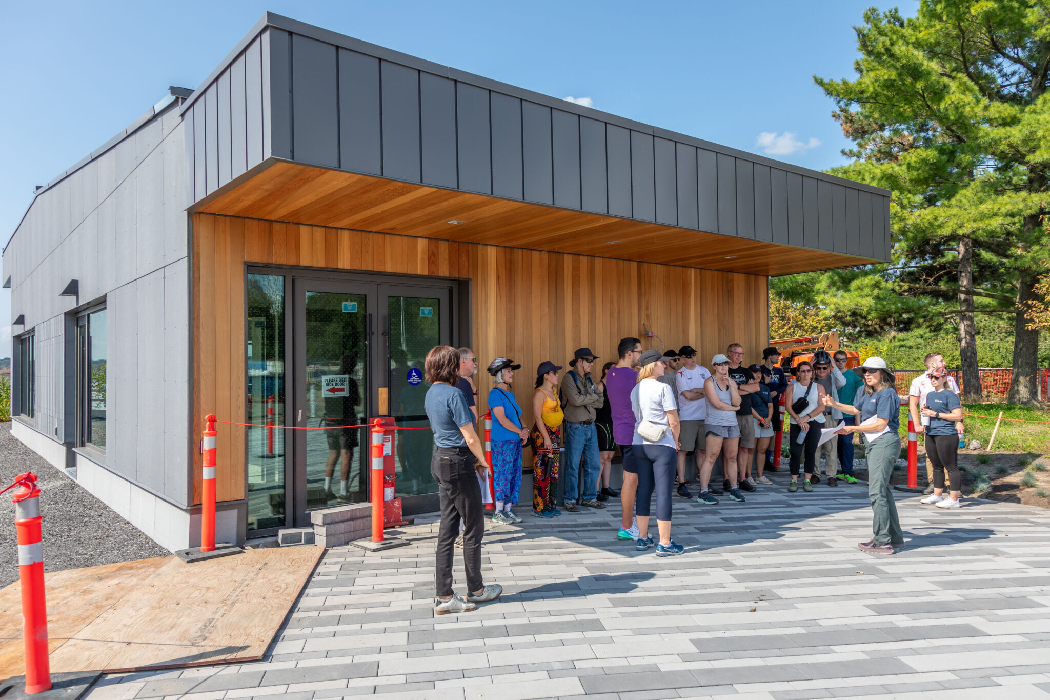 Groupe d’une quinzaine de personnes écoutant des instructions à l’ombre d’un bâtiment.